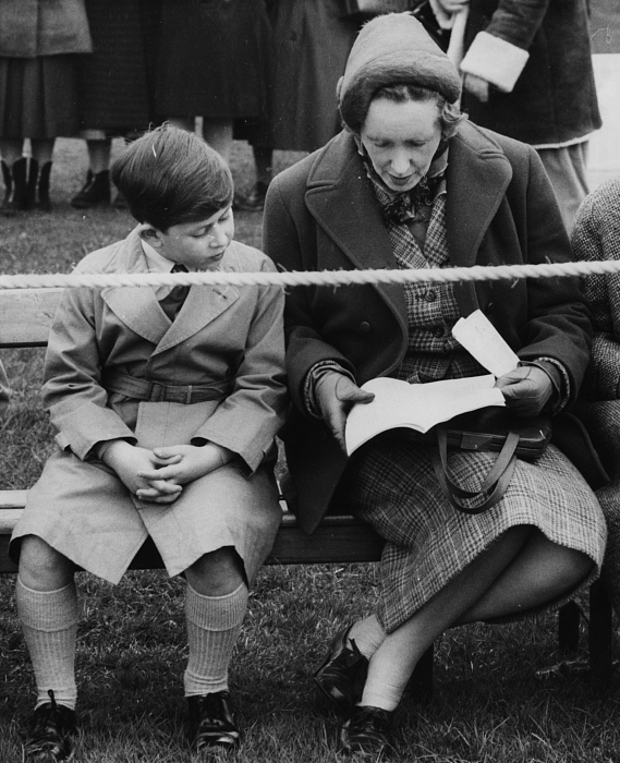 Юный принц Чарльз делится программой со своей соседкой, наблюдая за выступлением на Королевском конном шоу в Аскоте, 24 апреля 1958 года фото № 7