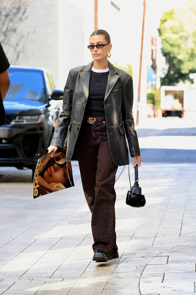 Кожаный жакет и мужские брюки: Хейли Бибер в винтажном луке сумела прорекламировать собственный бренд косметики фото № 1